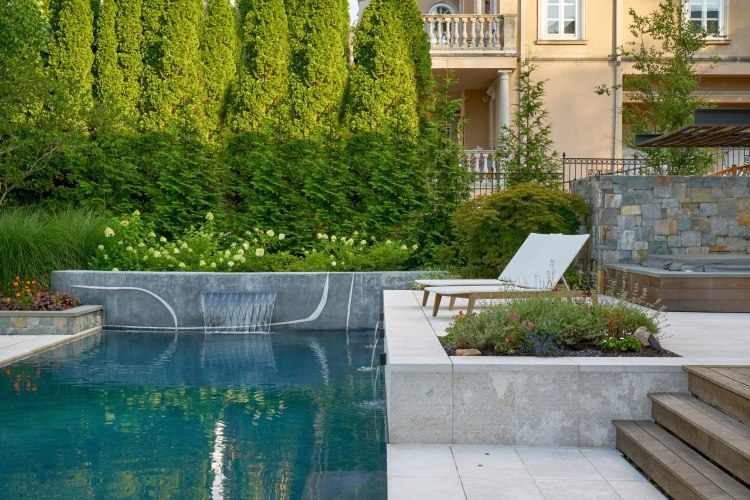 Beautifully landscaped outdoor living space with a pool, pool-side seating, and greenery.