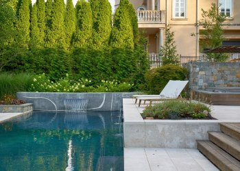 Beautifully landscaped outdoor living space with a pool, pool-side seating, and greenery.