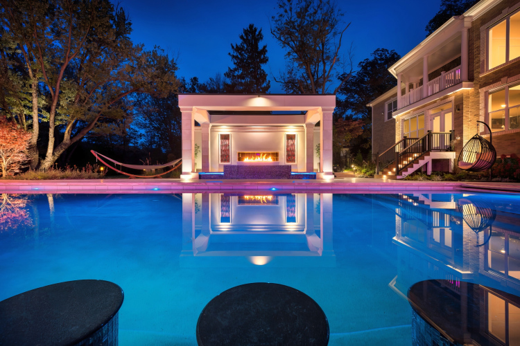 Night view of expansive pool patio with multiple seating areas