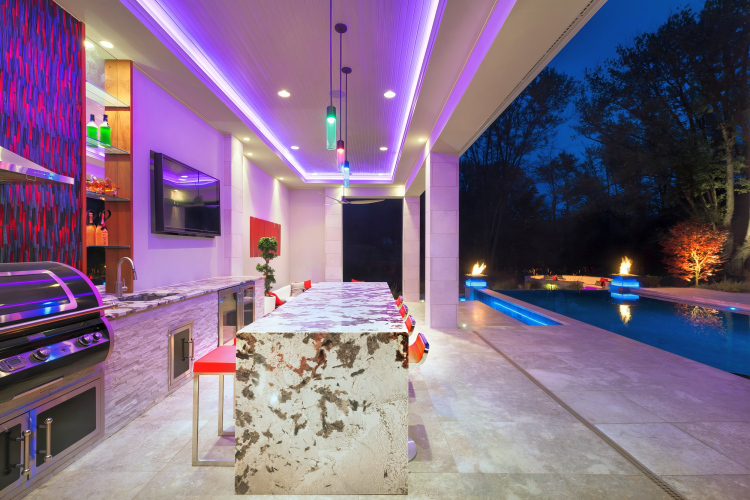 Impeccably designed outdoor kitchen and dining area in McLean lit up at night