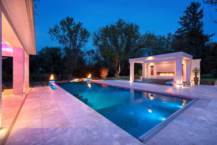 Custom pool in a luxurious setting, with modern design and color-changing landscape lighting.