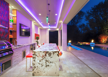 Impeccably designed outdoor kitchen and dining area in McLean lit up at night