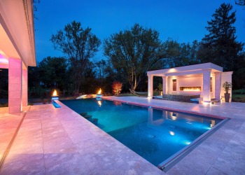 Custom pool in a luxurious setting, with modern design and color-changing landscape lighting.