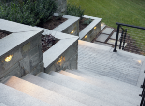 Steps leading to backyard with landscape lighting and custom masonry